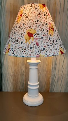 a lamp that is on top of a table with a curtain in the back ground