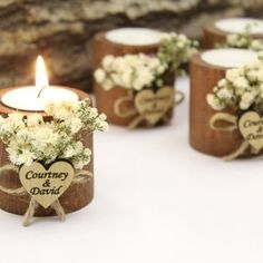 small wooden candle holders with white flowers and hearts on them, sitting next to a piece of wood