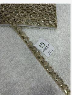 gold sequin trim on white fabric with tag for sale in the store or retail area