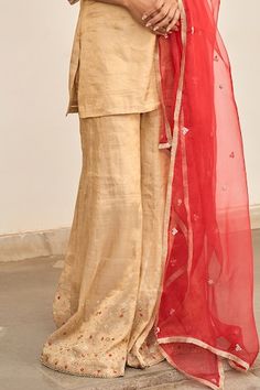 Gold kurta with placement hand embroidery. Paired with a sharara with hand embroidered hem and red dupatta with embroidered buttis. - Aza Fashions Festive Raw Silk Sharara For Ceremonial Occasion, Ceremonial Sharara With Dupatta For Eid, Eid Ceremonial Sharara With Dupatta, Festive Ceremonial Raw Silk Sharara, Ceremonial Dori Work Sharara For Diwali, Ceremonial Chanderi Sharara With Dupatta, Ceremonial Raw Silk Sharara For Diwali, Festive Silk Sharara For Ceremonial Occasions, Ceremonial Festive Silk Sharara