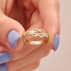 a woman's hand holding a gold ring with diamonds