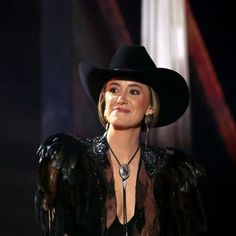 a woman wearing a black hat with feathers on it