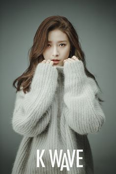 the girl is posing with her hands on her face and wearing a white knit sweater