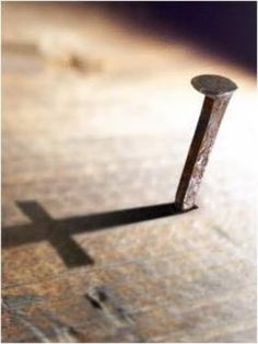 the shadow of a cross is cast on top of a piece of wood that has been nailed to it