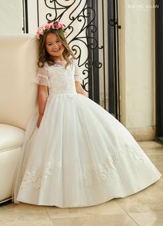 Your sweet girl will captivate the room in this long applique short sleeve dress with A-line skirt by Rachel Allan RB9145. Walk down the aisle in true elegance wearing Rachel Allan's beautiful tulle ballgown. This gorgeous gown is a beautiful sight to behold, with applique and beading details throughout. The sheer flowing sleeves will make any flower girl feel like a princess, and the lace-up back adds a unique touch. Perfect for any special occasion, this stunning dress will make her feel like Formal Tulle Dress With Short Sleeves, Fitted Tulle Ball Gown With Short Sleeves, Elegant Short Sleeve Tulle Ball Gown, Formal Tulle Gown With Short Sleeves, Short Sleeve Dress With Fitted Bodice For Confirmation, Fitted Tulle Gown With Short Sleeves, Short Sleeve Tulle Dress With Floral Applique, Fitted Tulle Gown For Confirmation, Short Sleeve Lace Confirmation Dress