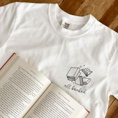 All Booked Tee – The Bookish Goods White Literary T-shirt With Letter Print, Bookish Cotton T-shirt With Letter Print, White Literary Letter Print T-shirt, Relaxed Fit Pre-shrunk Bookish T-shirt, White Bookish T-shirt As Gift, White Bookish T-shirt As A Gift, White Bookish Style T-shirt As Gift, Bookish Style White T-shirt As Gift, Literary Relaxed Fit Crew Neck T-shirt