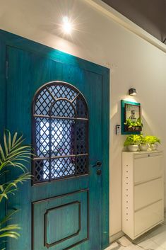 a green door with a window in the center and potted plants on the other side