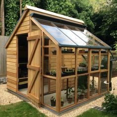 a small wooden greenhouse with lots of plants in it