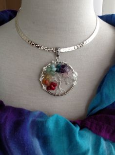 a woman wearing a necklace with flowers in the center and a silver disc on it