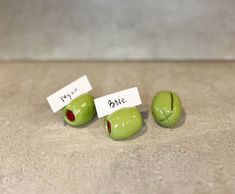 three green apples with faces and words on them sitting on the floor next to each other