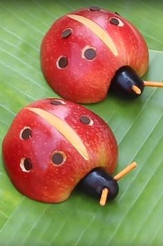 two red ladybugs sitting on top of a green leaf next to each other