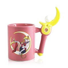 a pink coffee mug with a yellow handle and a sailor moon on the side, sitting next to it