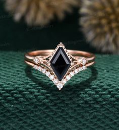 an engagement ring with black diamond and white diamonds on the side, sitting on a green surface