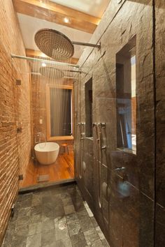 a bathroom with a shower, sink and toilet in it's stall area next to a brick wall