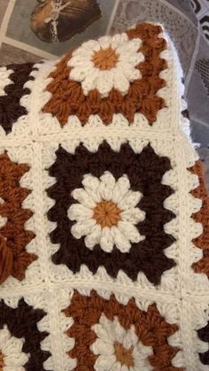 a crocheted blanket is laying on top of a table next to a magazine