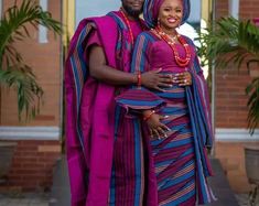 a man and woman dressed in traditional african clothing posing for the camera with their arms around each other