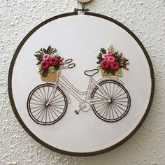 a bicycle with flowers on it is hanging from the wall in front of a white wall