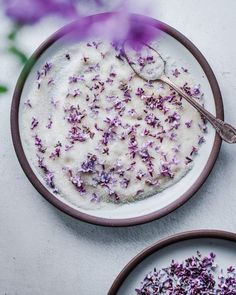 a bowl filled with purple flowers next to two plates full of rice and sprinkles