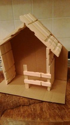 a cardboard model of a house made to look like it has a bench in the front