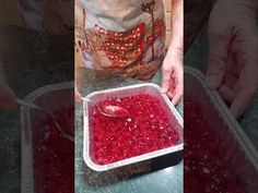 a person scooping raspberries into a container