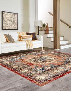 a living room with a couch, rug and stairs