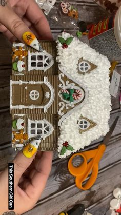 someone is decorating a gingerbread house with icing and decorations on the table