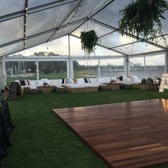 a party tent set up with couches, tables and flowers on the grass in front of it