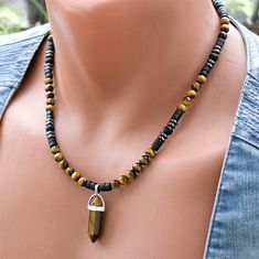 Unleash the captivating energy of this Tiger Eye Point Pendant Beaded Necklace, a stunning piece of boho stone jewelry. The focal point is a mesmerizing Tiger Eye Point Pendant, surrounded by a harmonious blend of 6mm round Tiger Eye and Matte Onyx beads. The rich, earthy tones extend to the black coconut wood beads, while hematite accent beads add a touch of sophistication. Crafted with precision using steel wire and a secure clasp, this necklace seamlessly combines style and durability for a u Adjustable Onyx Beaded Necklace In Bohemian Style, Bohemian Onyx Beaded Necklace With Black Beads, Bohemian Onyx Jewelry With Gemstone Beads, Bohemian Onyx Gemstone Beaded Jewelry, Handmade Bohemian Onyx Beaded Necklace, Adjustable Onyx Bohemian Beaded Necklace, Bohemian Handmade Hematite Jewelry, Black Bohemian Beaded Gemstone Necklace, Bohemian Onyx Necklace With Black Beads