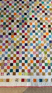 a multicolored quilt is displayed on the floor