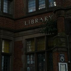 there is a sign that says library on the side of a brick building with windows