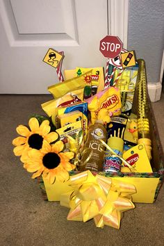 a yellow gift box filled with candy and sunflowers next to a white door