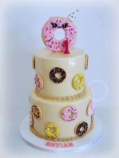 a three tiered cake decorated with donuts and sprinkles