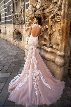 a woman in a wedding dress leaning against a wall with her back to the camera