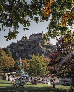 people sitting on lawn chairs in front of an old castle with trees and grass around it