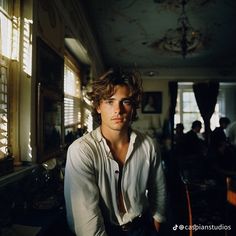 a young man is posing for a photo in a room full of people and sunlight coming through the windows