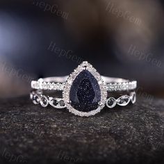 a pear shaped blue diamond ring on top of a rock with diamonds around the band