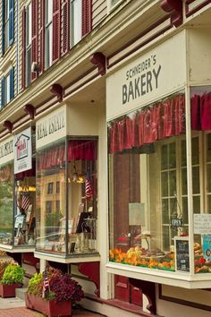 the storefronts are decorated with red and white awnings, along with flower boxes on the sidewalk