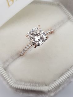 an engagement ring in a velvet box with a diamond on the band and side stones