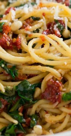 pasta with spinach, sun dried tomatoes and parmesan cheese in a white bowl