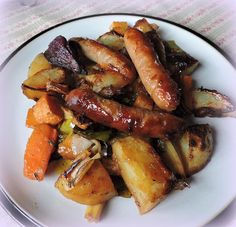 a white plate topped with sausages and potatoes