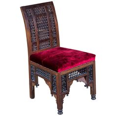 an ornate wooden chair with a red velvet seat pad on the bottom and back side