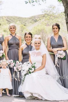 a group of women standing next to each other wearing dresses and holding bouquets in their hands