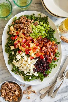 a white plate topped with lots of food next to two bowls filled with fruit and veggies