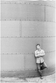 a man standing in front of a large metal tank with his arms crossed and looking at the camera