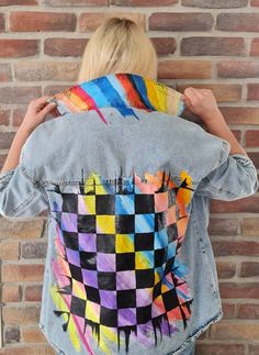 a woman is wearing a jean jacket with colorful designs on the back and sides,