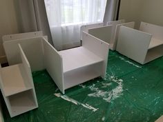 some white furniture sitting on top of a green tarp in front of a window