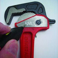 a hand holding a wrench with the word rm on it's side and another tool in front of it