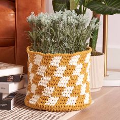 a crocheted planter sitting on top of a table next to a book