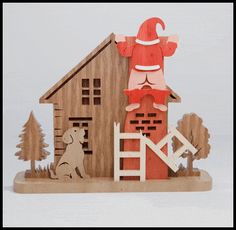 a wooden house with a santa clause on it's roof and a dog in the yard