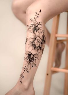 a woman's leg with black and white flowers tattooed on the side of her legs